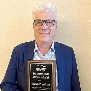 Greg holds award plaque